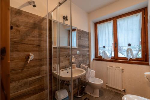 a bathroom with a sink and a toilet and a shower at San Luigi - Rooms & Apartments in Campodolcino