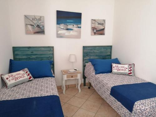 2 camas en una habitación con sábanas azules y una mesa en L'Ancora Blu en Marina di Modica