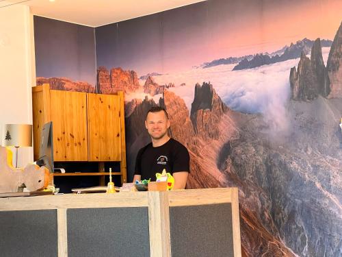 a man standing in front of a mural of mountains at Guesthouse Rosengarten in Dobbiaco