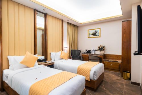 ein Hotelzimmer mit 2 Betten und einem Schreibtisch in der Unterkunft Marine Inn Hotel in Kochi