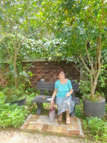 a woman sitting on a bench under a tree at Ceylon Kingsmen Garden - Katunayake Airport Transit Hotels in Negombo