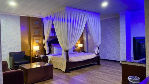 1 dormitorio con cama con dosel y sofá en Huang Xing Motel en Pingtung City