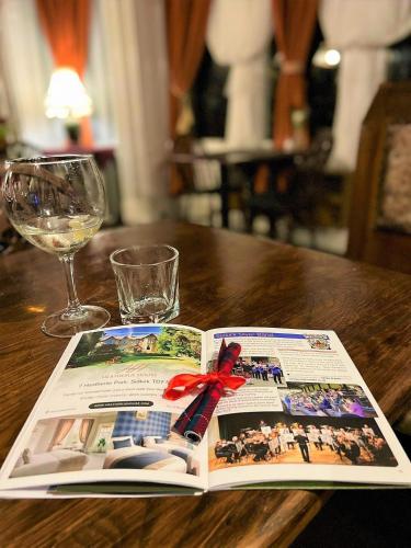 a book on a wooden table with a glass of wine at Heatherlie House Hotel in Selkirk