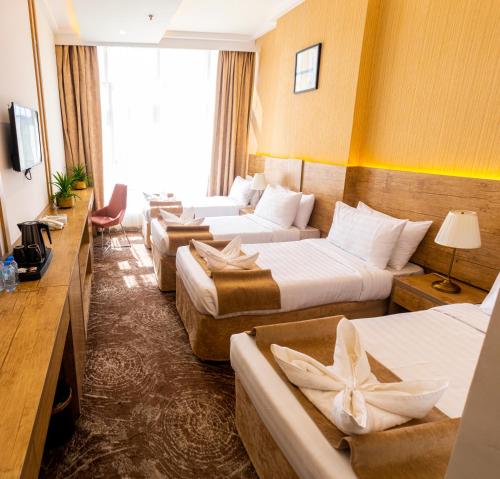 a hotel room with three beds and a television at Emaar Legend in Makkah