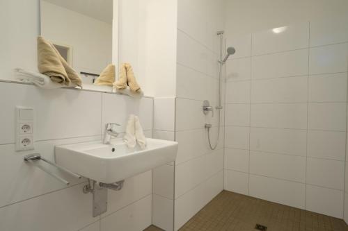 a white bathroom with a sink and a shower at Lounge Maritime direkt am Meer, Strand fußläufig erreichbar, barrierefrei in Kappeln