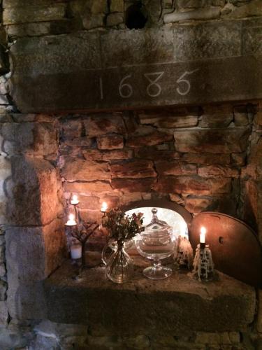 a stone fireplace with candles and a clock on it at L'arbre à chapeaux in La GrandʼCombe-Châteleu