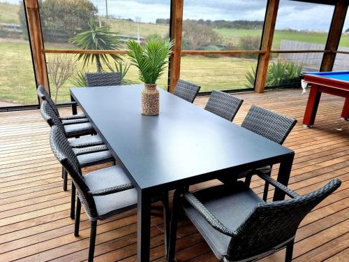 a black table and chairs on a deck at London Bridge Holiday Home in Port Campbell