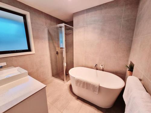 a bathroom with a tub and a shower and a sink at London Bridge Holiday Home in Port Campbell