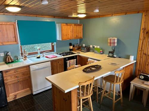 a kitchen with wooden cabinets and a counter top at Craiglea Cottage, self catering highland cottage. in Fort William