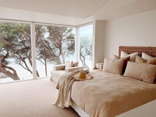 a bedroom with a large bed with a large window at The Cove Beach Front Luxury House in Port Fairy