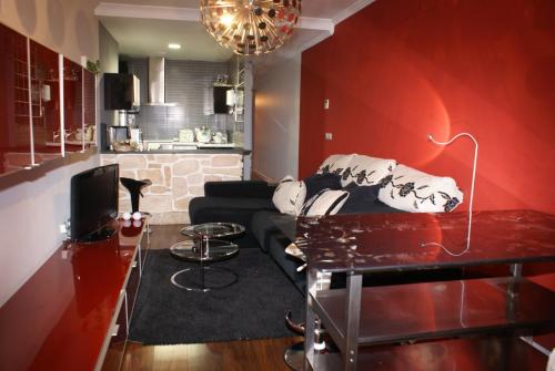 Precioso Apartamento - Casco Antiguo de Talavera في تالافيرا دي لا رينا: غرفة معيشة مع أريكة سوداء وجدار احمر