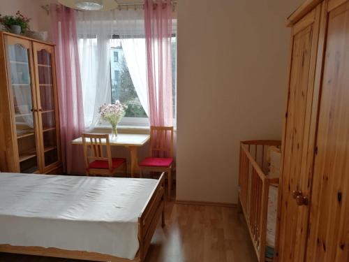 a bedroom with a bed and a table and a window at Apartament Balladyny in Gdynia