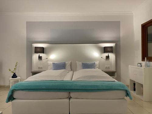 um quarto com uma grande cama branca e 2 luzes em Haus Heidelerche das ThermePlus-Haus em Bad Bevensen