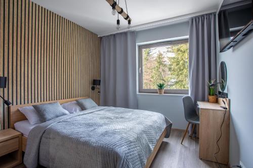 a bedroom with a bed and a window and a desk at Stone Hill Apartament Wellness z basenem jakuzi saunami prywatnym garażem i rowerami w cenie in Szklarska Poręba