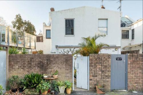 a white house with a brick fence and plants at Rear studio with open space in Sydney