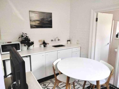 a kitchen with a white table and a white table and chairs at Rear studio with open space in Sydney