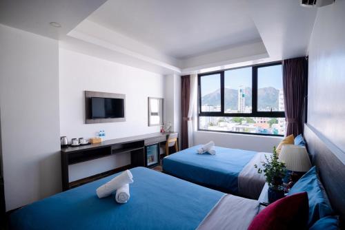 a hotel room with two beds and a television at La Casa Hotel Nha Trang in Nha Trang