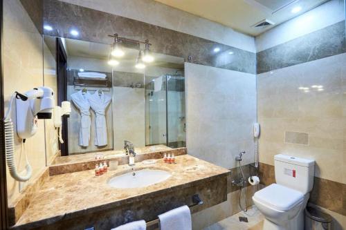 a bathroom with a sink and a toilet and a mirror at Smith's Hotel in Baku