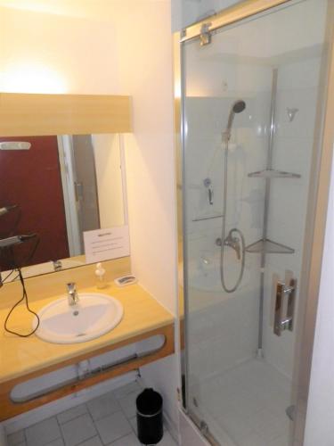 une salle de bain avec une douche, un lavabo et un miroir dans l'établissement T2 PLAGE DE LA CONQUE, au Cap d'Agde