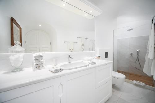 a white bathroom with a sink and a toilet at The Tsitouras Collection in Firostefani