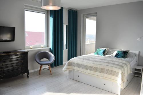 a bedroom with a bed and a chair and windows at Apartament Martini in Kołobrzeg