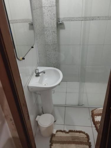 a white bathroom with a sink and a toilet at Cantinho Nativus in Maragogi