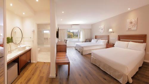 um quarto de hotel com duas camas e uma casa de banho em StradivariuS Hotel Boutique em Villa General Belgrano