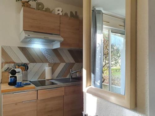 cocina con armarios de madera, fregadero y ventana en Dolce vita en centre ville, en Niort