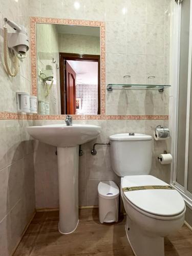 a bathroom with a sink and a toilet and a mirror at Beatriz Charming Hostal in Torremolinos