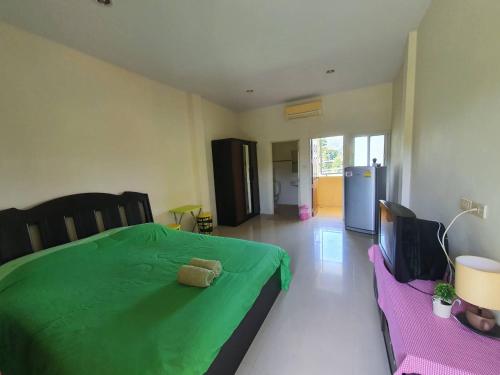 a bedroom with a green bed with a teddy bear on it at Bansuanrimnam Pakchong Resort in Pak Chong