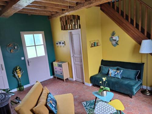 a living room with a green couch and yellow walls at Les suites d'Élise - Suite Louane in Grumesnil