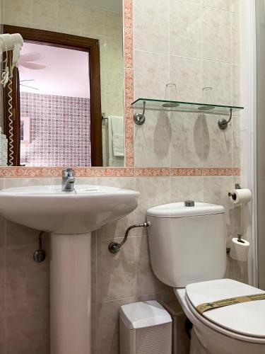 a bathroom with a sink and a toilet and a mirror at Beatriz Charming Hostal in Torremolinos