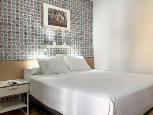 a white bed in a room with a wall at Beatriz Charming Hostal in Torremolinos