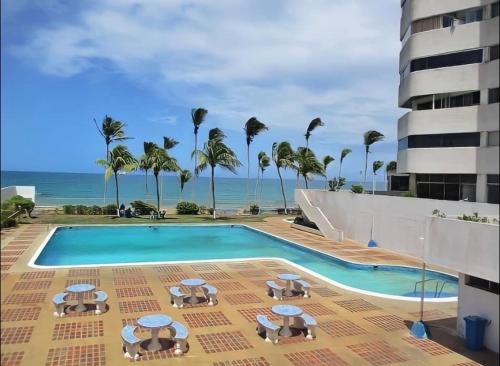 波拉馬的住宿－*Tulli Apartmentos Margarita Island*，一个带椅子和遮阳伞的游泳池以及大海