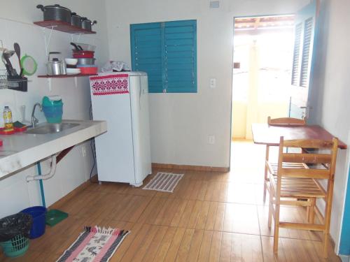 a kitchen with a white refrigerator and a wooden floor at Chalé Panulirus in Icapuí