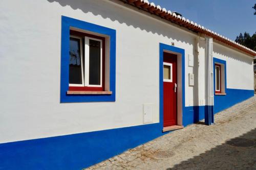 un edificio blanco y azul con puertas rojas y azules en Casa do Vale - Valley House, en Odeceixe