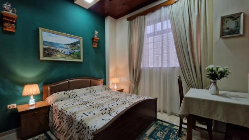 a bedroom with a bed and a table and a window at Vila Korani in Tirana