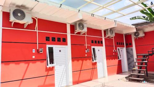- un bâtiment rouge avec des portes et des fenêtres blanches dans l'établissement D'Ariska Rooms Homestay, à Jombang