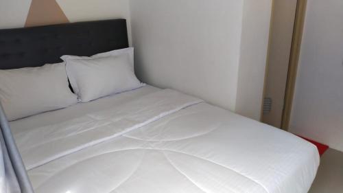 a bed with white sheets and pillows in a room at D'Ariska Rooms Homestay in Jombang