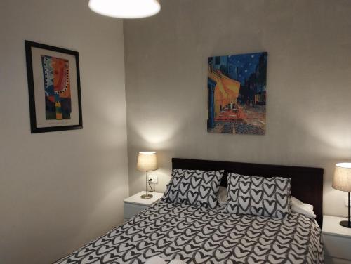 マルグラット・デ・マルにあるDay Ok Beach Apartmentのベッドルーム1室(ランプ2つ、絵画付)