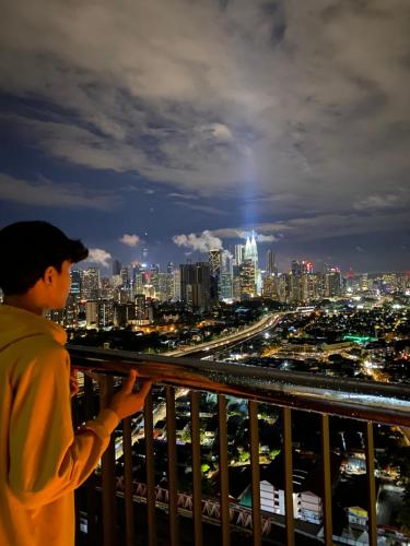 Datum Jelatek Sky Residence KLCC SkyRing Linked to LRT and Mall في كوالالمبور: رجل يقف على شرفة يطل على مدينة في الليل