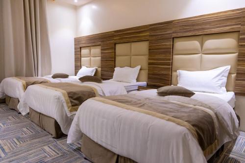 a hotel room with three beds in a room at منــازل الماسة للشقق المخدومة عنيزة in Unayzah