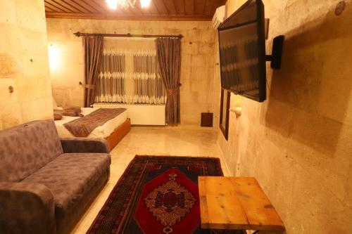 a room with two beds and a tv and a couch at Roma Cave Suite in Goreme