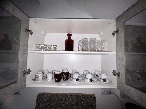 un estante con tazas y una botella en una habitación en Casa Camelia, en Nehoiu