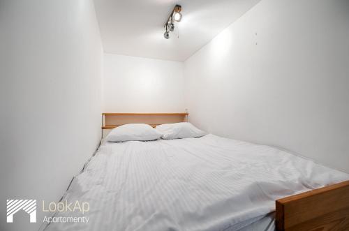 1 dormitorio con 1 cama blanca y 2 almohadas en Loft Morski by LookAp, en Łódź