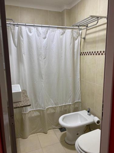 y baño con cortina de ducha blanca y aseo. en Edificio Giu 2 en San Salvador de Jujuy