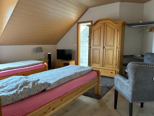 1 dormitorio con 2 camas, armario y silla en Pension Zum Paradies en Harthausen