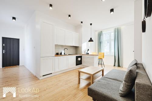 uma sala de estar com um sofá e uma cozinha em Piotrkowska Street I by LookAp em Lódź