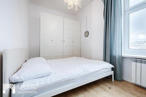 uma cama branca num quarto com uma janela em Piotrkowska Street I by LookAp em Łódź