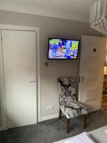 Zimmer mit einem Stuhl und einem TV an der Wand in der Unterkunft Southfork Villa Guesthouse in Callander